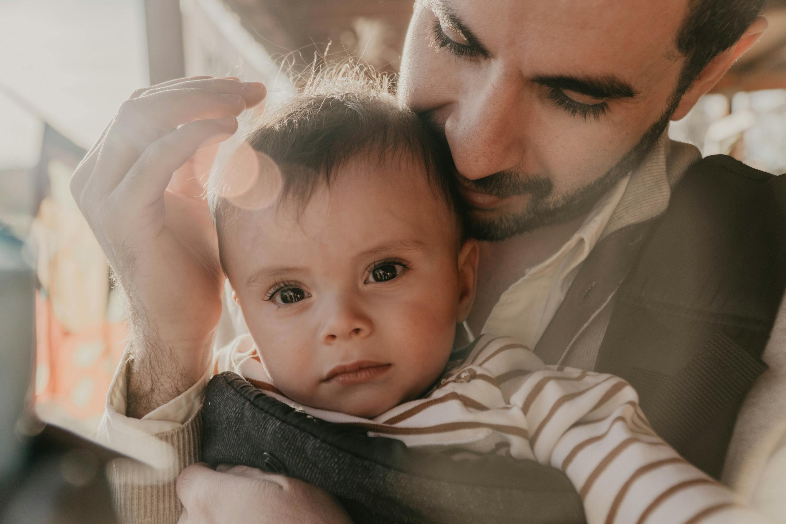 A father lovingly holds his child in a warm embrace during a sunny day in Portland.